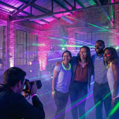 Group photo under neon glow party lighting during event Group photo under neon glow party lighting during event
