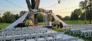 wedding_arch_with_drapery_flowers_string_lighting-min