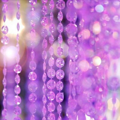 Close-up of crystal chandelier pillar with glowing beaded crystals at a wedding
