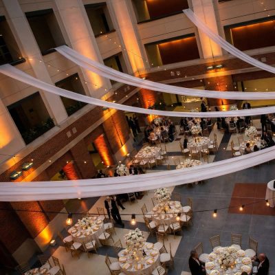 Outdoor string lights mounted across courtyard wedding reception