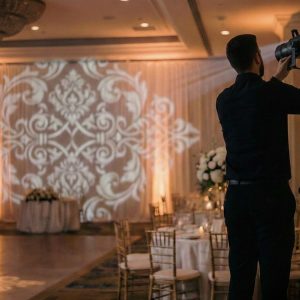Tech adjusting gobo lighting on draping backdrop for wedding